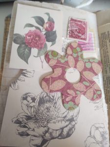 A few different bits of paper, a couple of stamps and a big wooden flower shape placed on the page to test the water